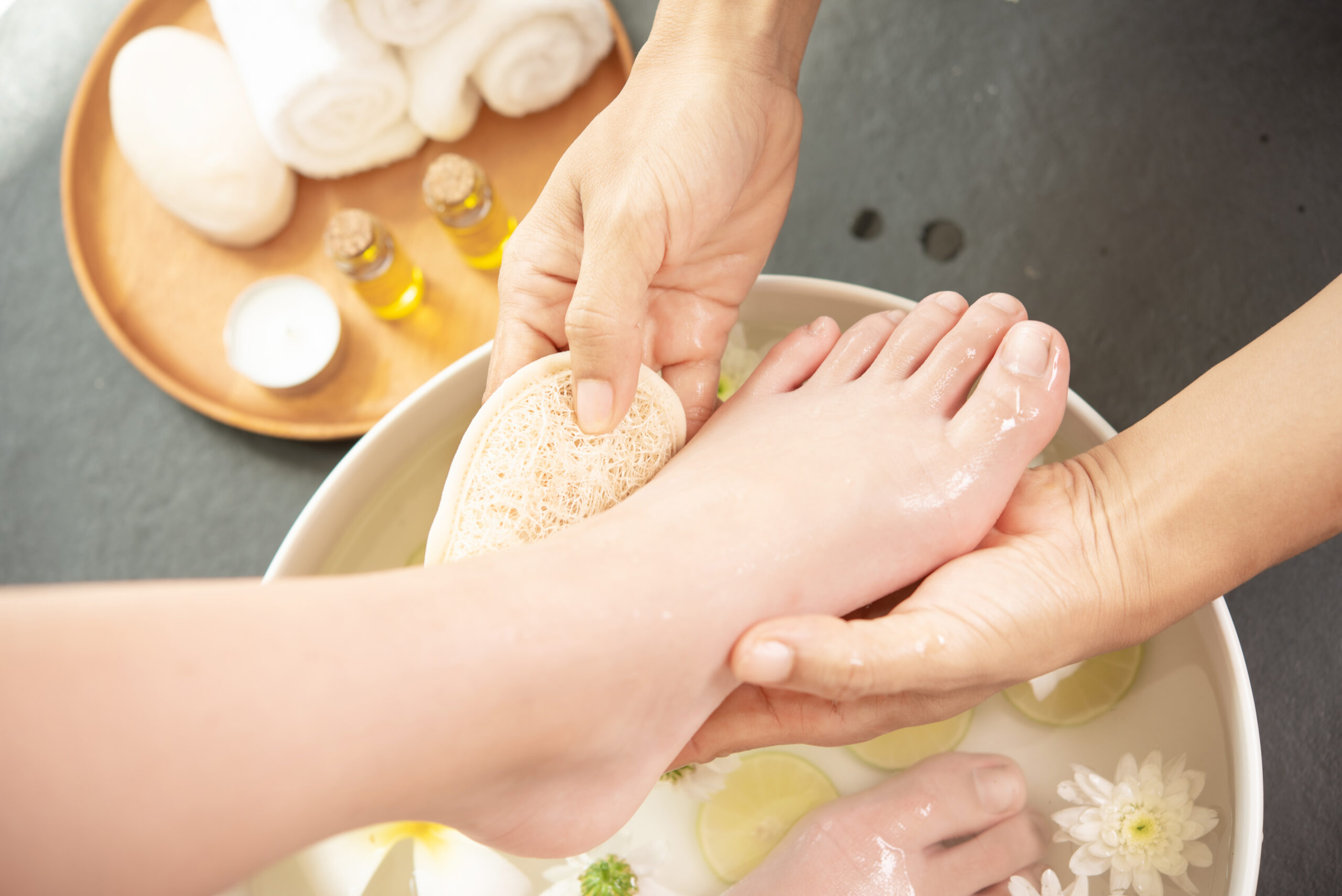 foot washing in spa before treatment. spa treatment and product for female feet and hand spa. white flowers in ceramic bowl with water for aroma therapy at spa.