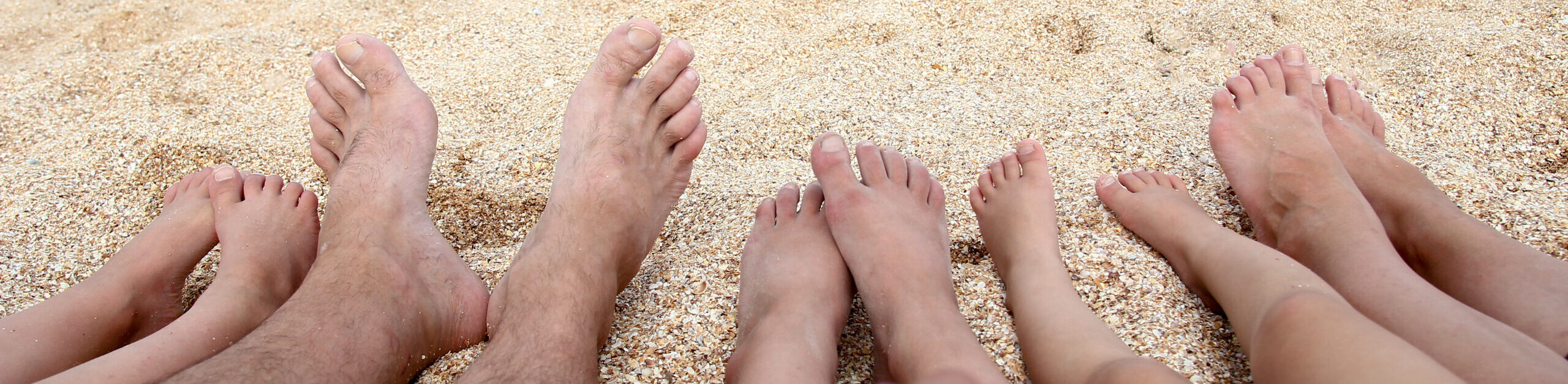 legs-beautiful-whole-family-sand-near-sea-background-scaled-e1714498173244.jpeg